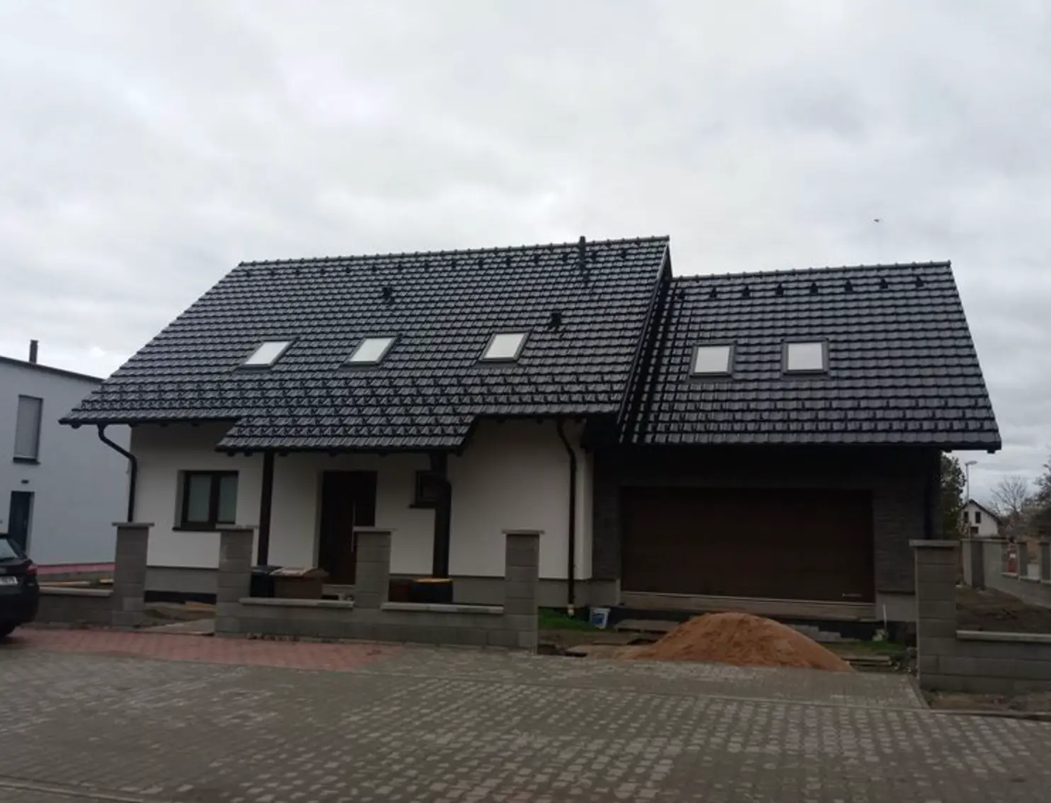 Családi ház tetőtéri ablakokkal felhős égen